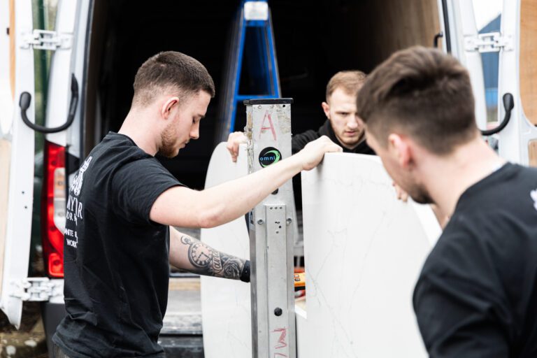 Mayfair Worktops Stonemasons handling a White Macaubus Quartz worktop slab during fitting preparation
