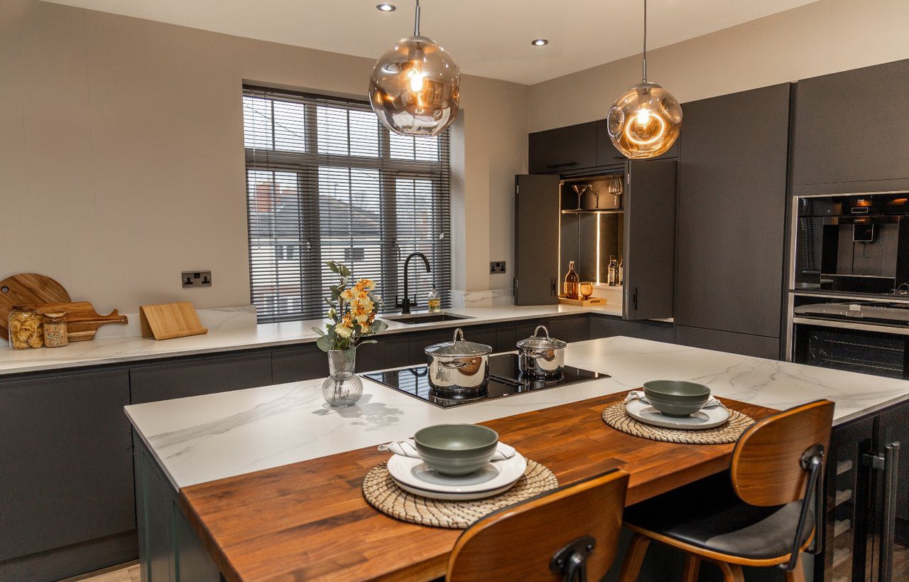 Volakas White Porcelain island worktop with subtle grey veining, shown with pendant lighting and dining place settings.