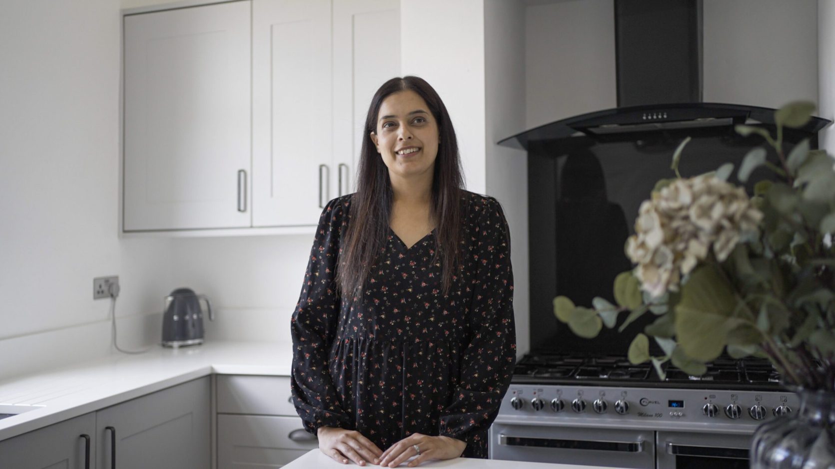 Nadiya customer testimonial image in her kitchen with Classic White Quartz worktops visible in the background