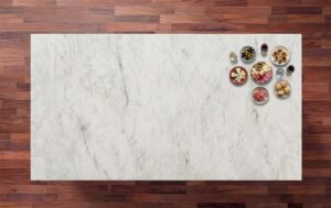 Carrara Venato Gold Porcelain worktop surface in soft white with light grey veining and warm gold toned accents, photographed from above with small bowls