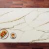 Calacatta Vagli Gold Porcelain worktop surface with warm gold veining across a white slab, styled with a small dish and coffee cup