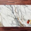 Calacatta Gold Borgnini Porcelain slab with a bright white base, bold grey veining and warm gold accents, photographed on a wood background