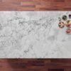 Calacatta Super White Porcelain slab with a bright white base and layered grey veining, photographed on a wood background with small props