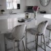 Modern kitchen featuring Statuario Bianco Porcelain island with bar stools and bright white cabinetry