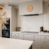 White Concrete Quartz worktop run with matching splashback behind the hob in a light shaker kitchen