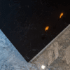 Emperor Black Quartz worktop corner shown from above with subtle pale veining on a polished black surface