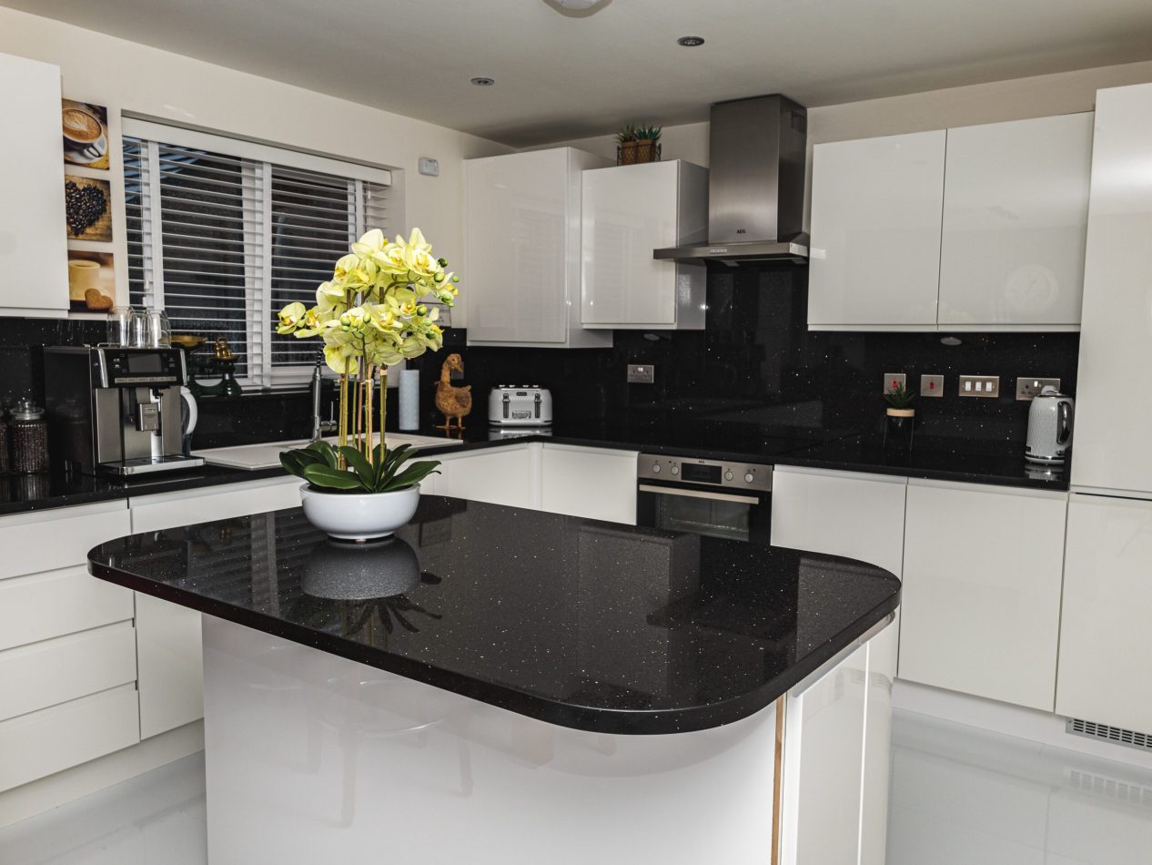 Wide kitchen view featuring a Black Starlight Quartz island with a curved end and subtle sparkle finish