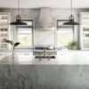 Bergen Porcelain island with a light stone effect and soft grey veining, shown as a waterfall edge centrepiece in a bright kitchen