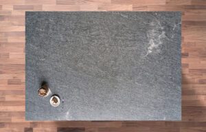 Overhead view of Diamond Galaxy leather Granite worktop showing a dark grey textured surface with subtle natural movement, photographed from above with styling near the edge.