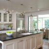 Bright kitchen view with a honed Absolute Black Granite island worktop, showing the matte black surface with a sink and tap set into the island.