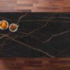 Top-down view of a Laurent Porcelain surface with gold veining on a dark background, styled with small dishes in the corner.