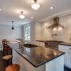 Wide view of a modern kitchen with Steel Grey Granite worktops on the island and perimeter run, showing bar seating and pendant lighting above the island.