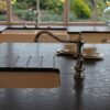 Sink area in Steel Grey leather Granite with drainer grooves and an inset sink, showing the textured finish around a chrome tap by the window.