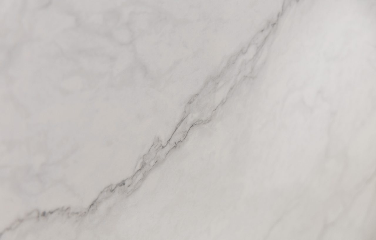 Statuario Venato Porcelain slab detail with a stronger grey diagonal vein and fine branching lines on a pale background.