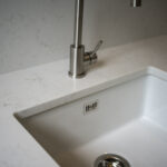 Carrara Quartz worktop around a white inset sink in a contemporary laundry room