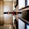 Side view along an Absolute Black Granite island worktop showing the polished edge and overhang, with bottles and glasses styled on the surface.