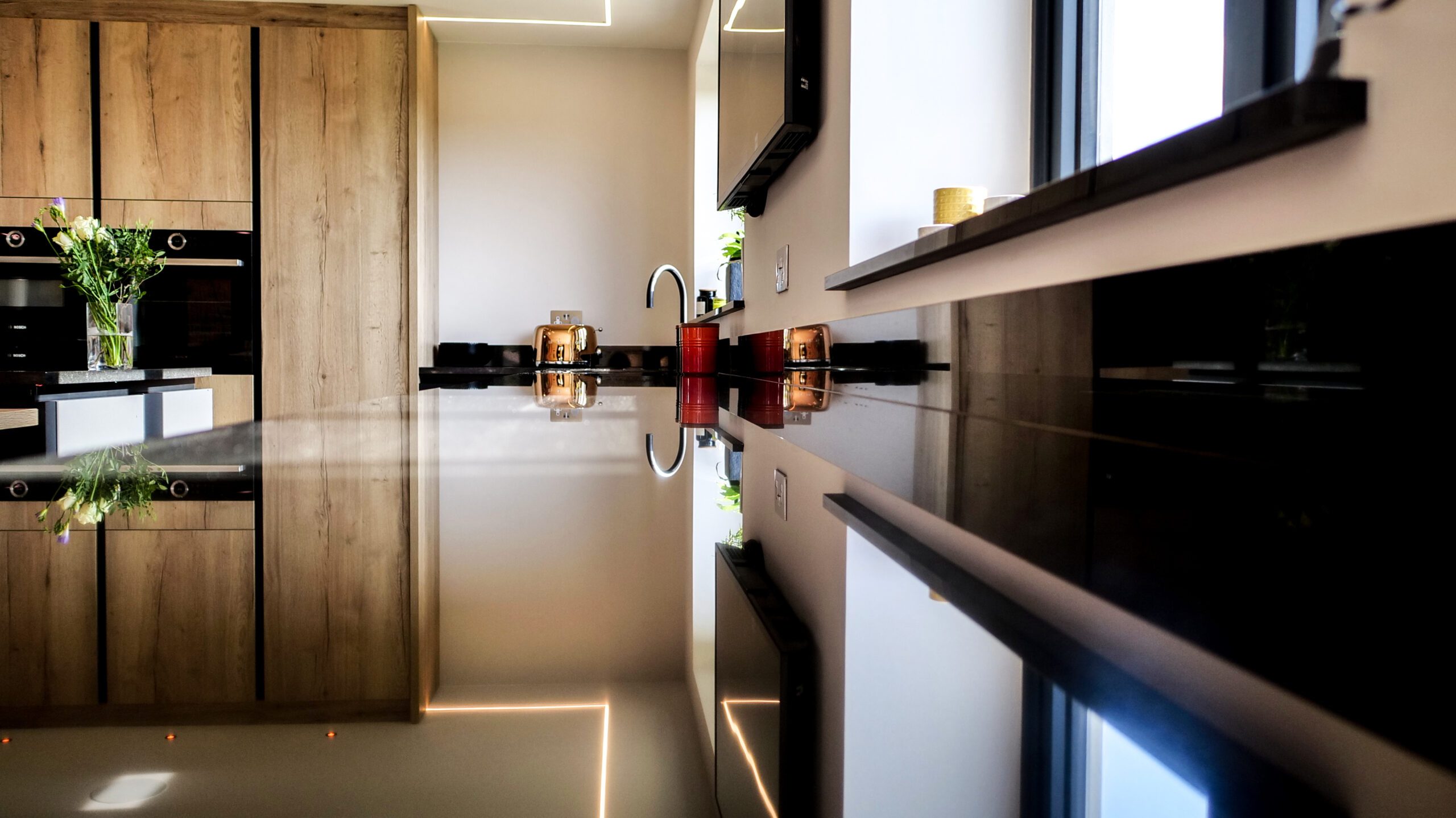 Low side angle of an Absolute Black Granite island worktop showing the polished edge and overhang with bottles and glasses on the worktop.
