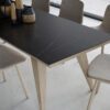 Kelya Porcelain tabletop in deep charcoal with a diagonal white vein, styled with dining chairs