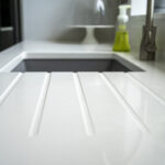 Classic White Quartz drainer grooves beside an inset sink, showing a smooth white surface finish
