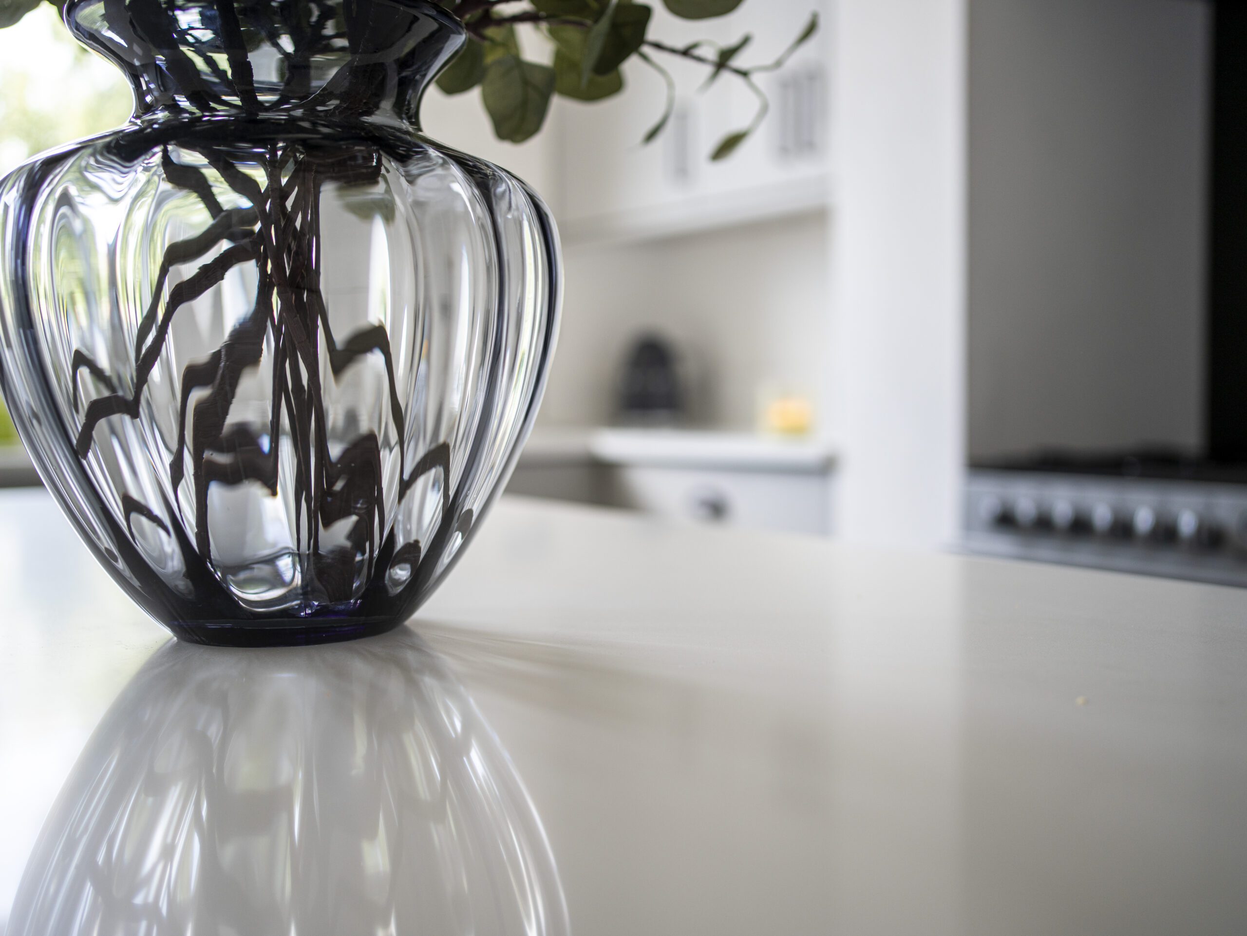 Classic White Quartz island worktop surface with a vase, showing a smooth white finish and light reflection