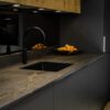 Laurent Porcelain worktop with gold veining featuring a flush black induction hob and matching upstand in a dark kitchen.