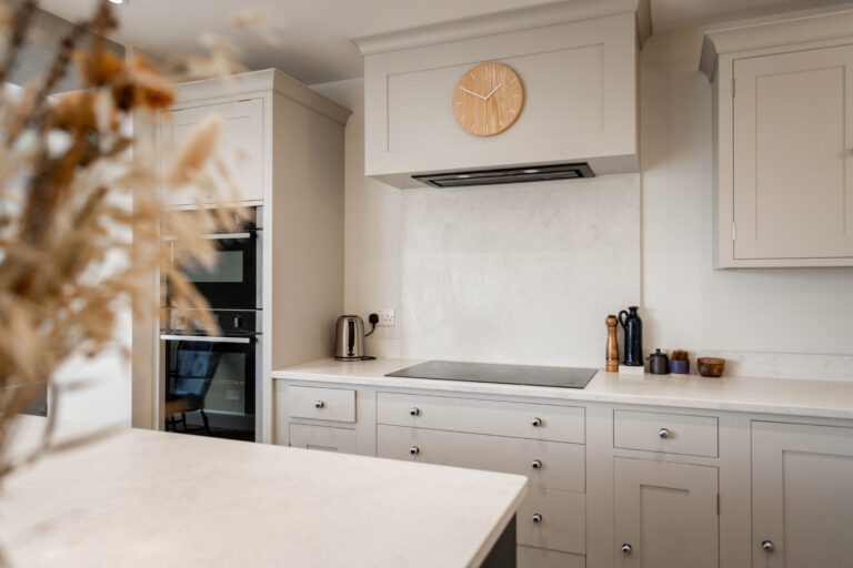 White Concrete Quartz worktop run with matching splashback behind the hob in a light shaker kitchen