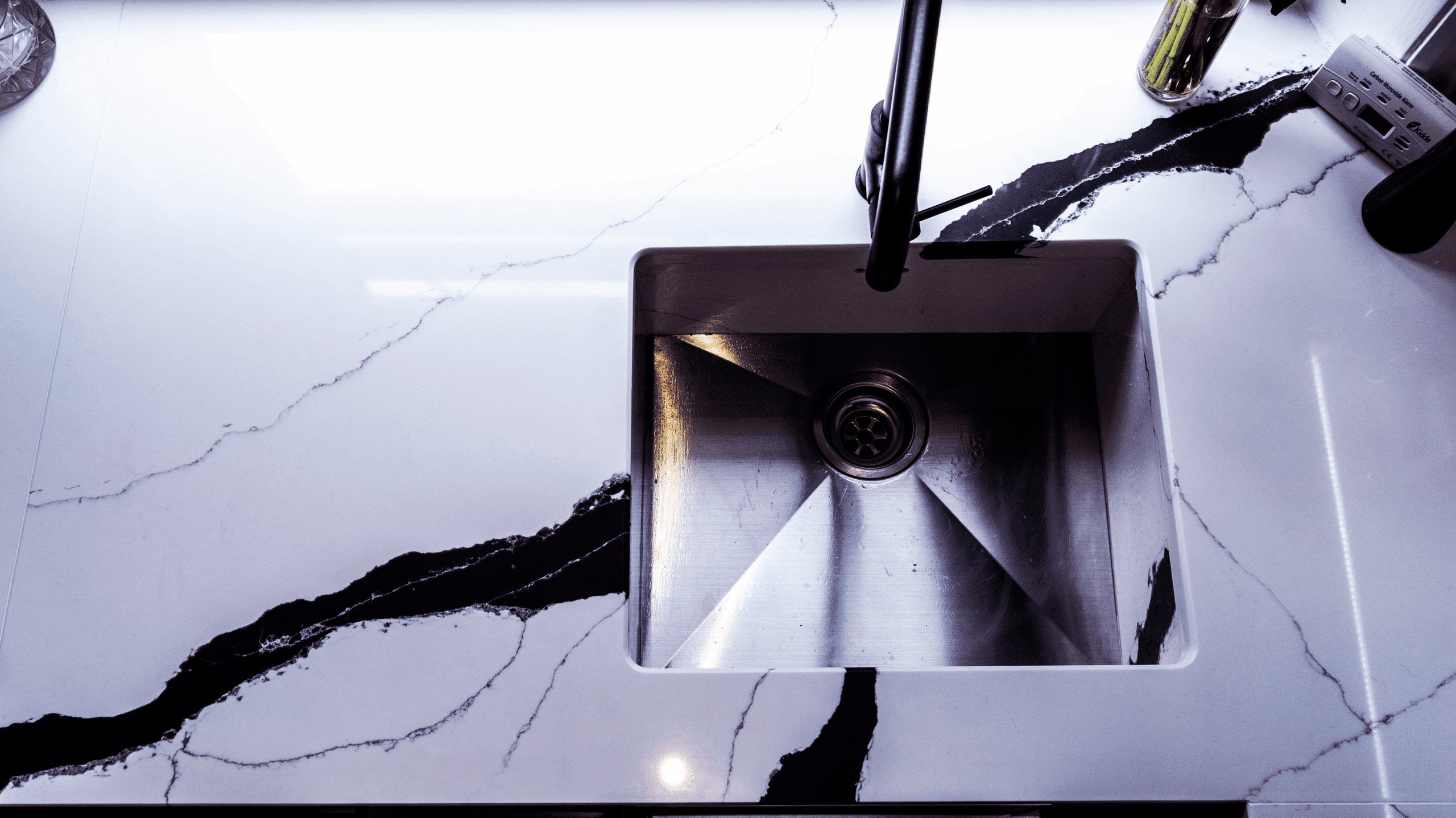 Black Calacatta Quartz worktop with inset sink shown in close-up with bold veining and polished white surface