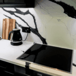 Black Calacatta Quartz worktop and splashback with bold black veining behind an induction hob in a modern kitchen