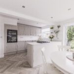 Open-plan kitchen with Bluetta Carrara Quartz worktops on the island and perimeter runs, showing a clean white finish