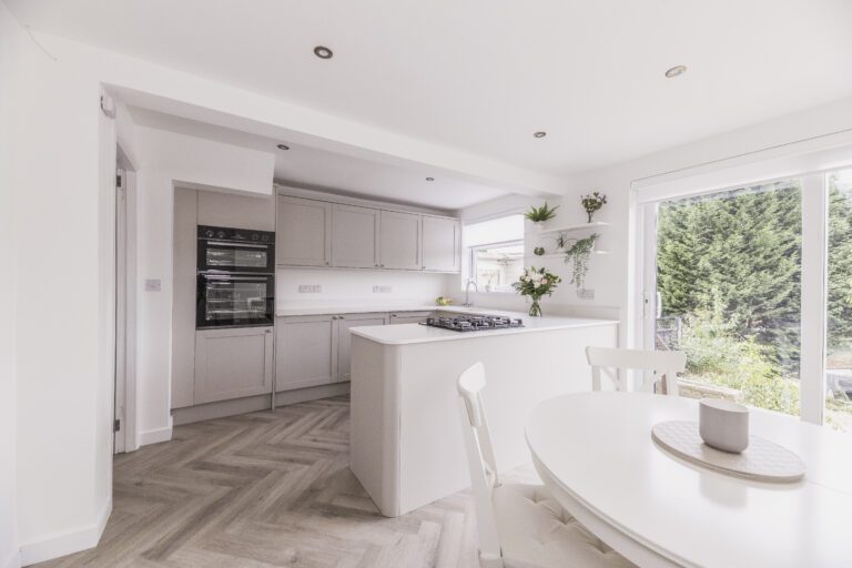 Open-plan kitchen with Bluetta Carrara Quartz worktops on the island and perimeter runs, showing a clean white finish