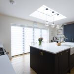 Blanco Zeus Quartz island worktop in an open-plan kitchen with bright white surface and pendant lights above