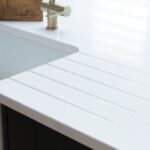 Blanco Zeus Quartz worktop with integrated drainer grooves beside an undermount sink and brass tap