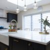 Blanco Zeus Quartz island worktop with bright white surface and brass tap in a modern kitchen