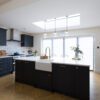 Open-plan kitchen with Blanco Zeus Quartz island worktop and bright white surface contrasting dark cabinetry
