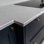 Carrara Quartz worktop on navy kitchen cabinets with copper handles