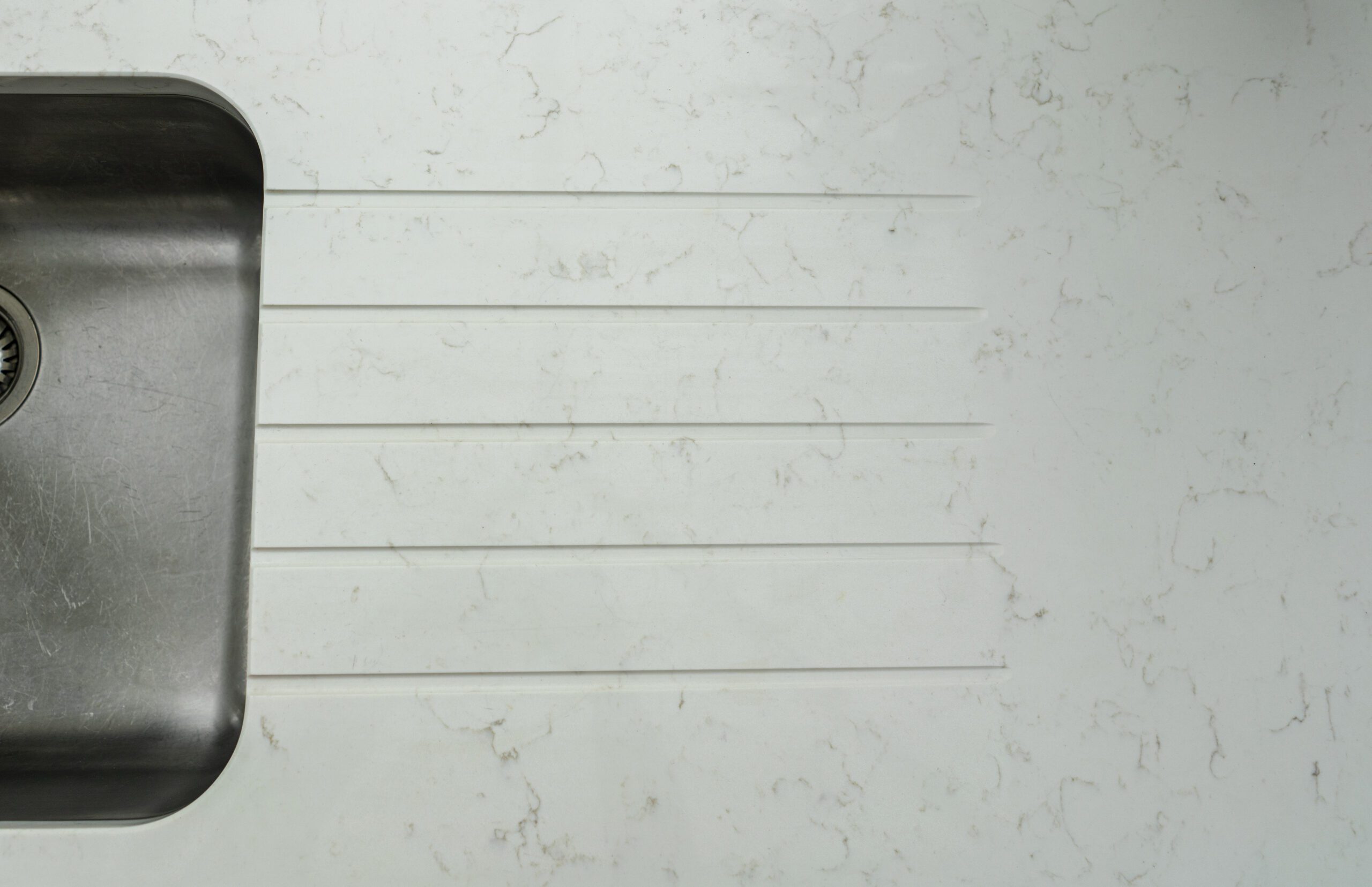 Carrara Quartz worktop with drainer grooves above a stainless steel sink