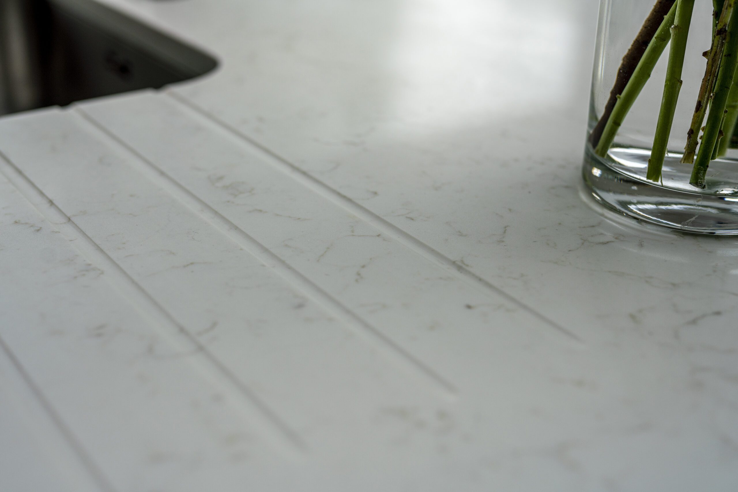 Drainer grooves cut into Carrara Quartz worktop beside stainless steel sink