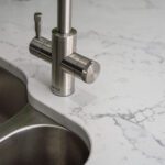 Chrome tap and double sink set into White Calacatta Quartz worktop with grey veining