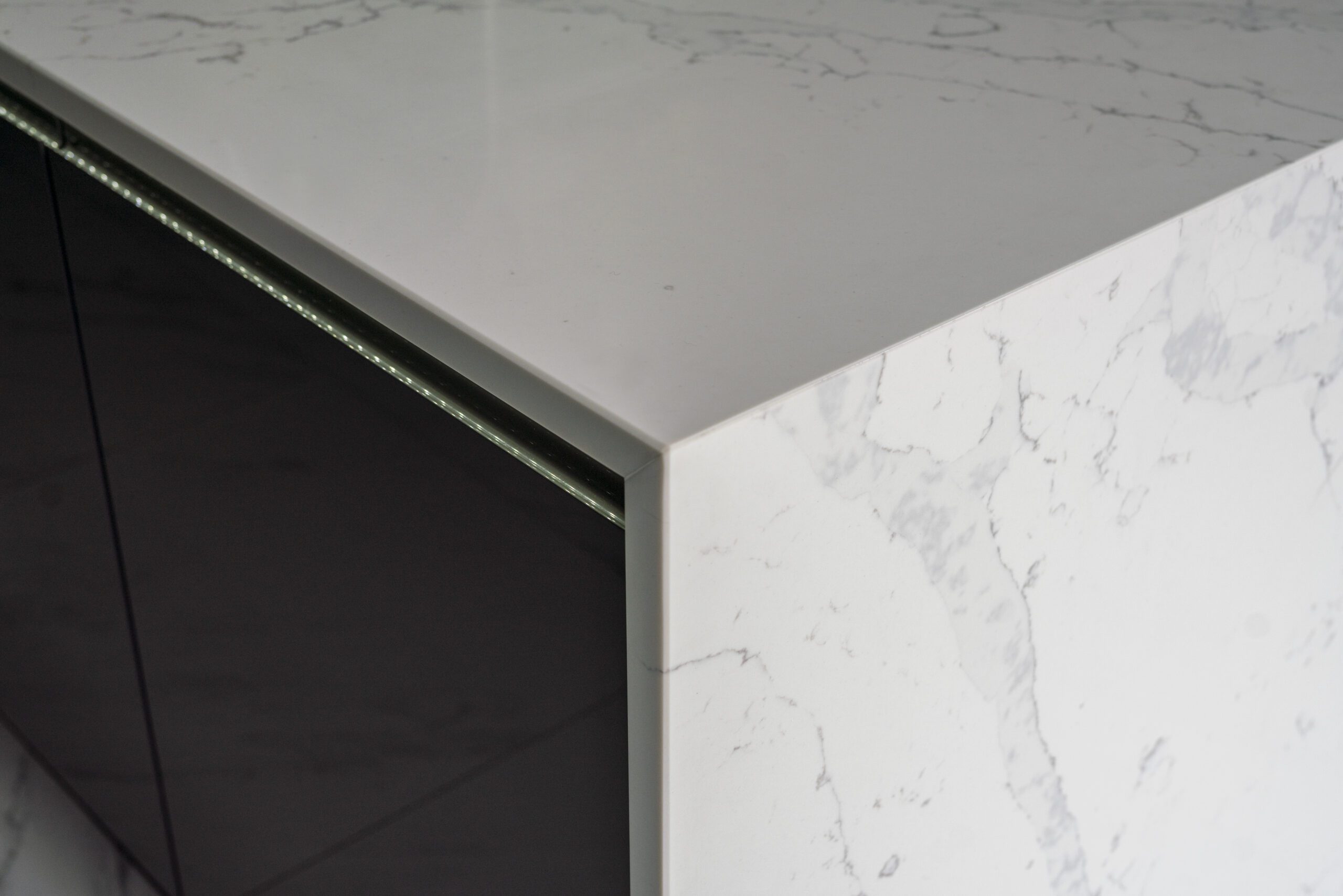 White Calacatta Quartz waterfall island corner showing polished edge and grey veining