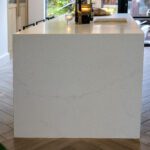 End view of an Olympus White Quartz kitchen island showing the smooth white finish and subtle veining
