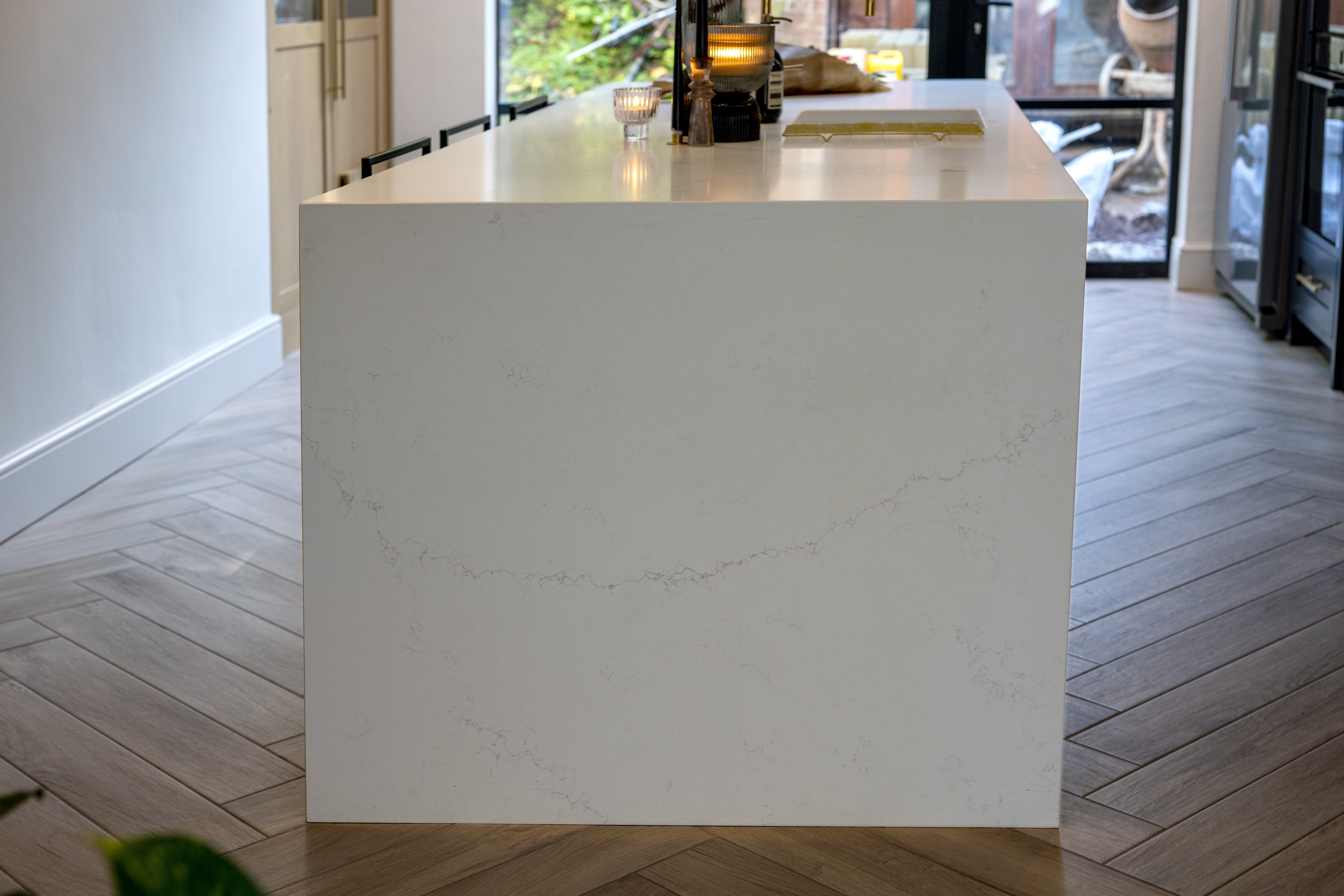 End view of an Olympus White Quartz kitchen island showing the smooth white finish and subtle veining