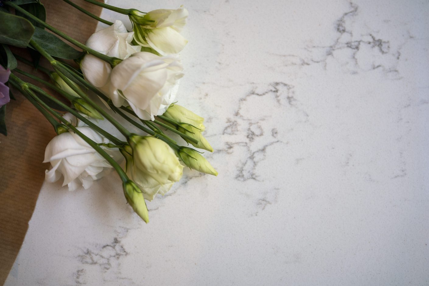 Close-up of Olympus White Quartz worktop showing soft veining with flowers placed on the surface