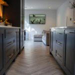 Long kitchen view with an Olympus White Quartz island worktop running through the centre of dark cabinetry