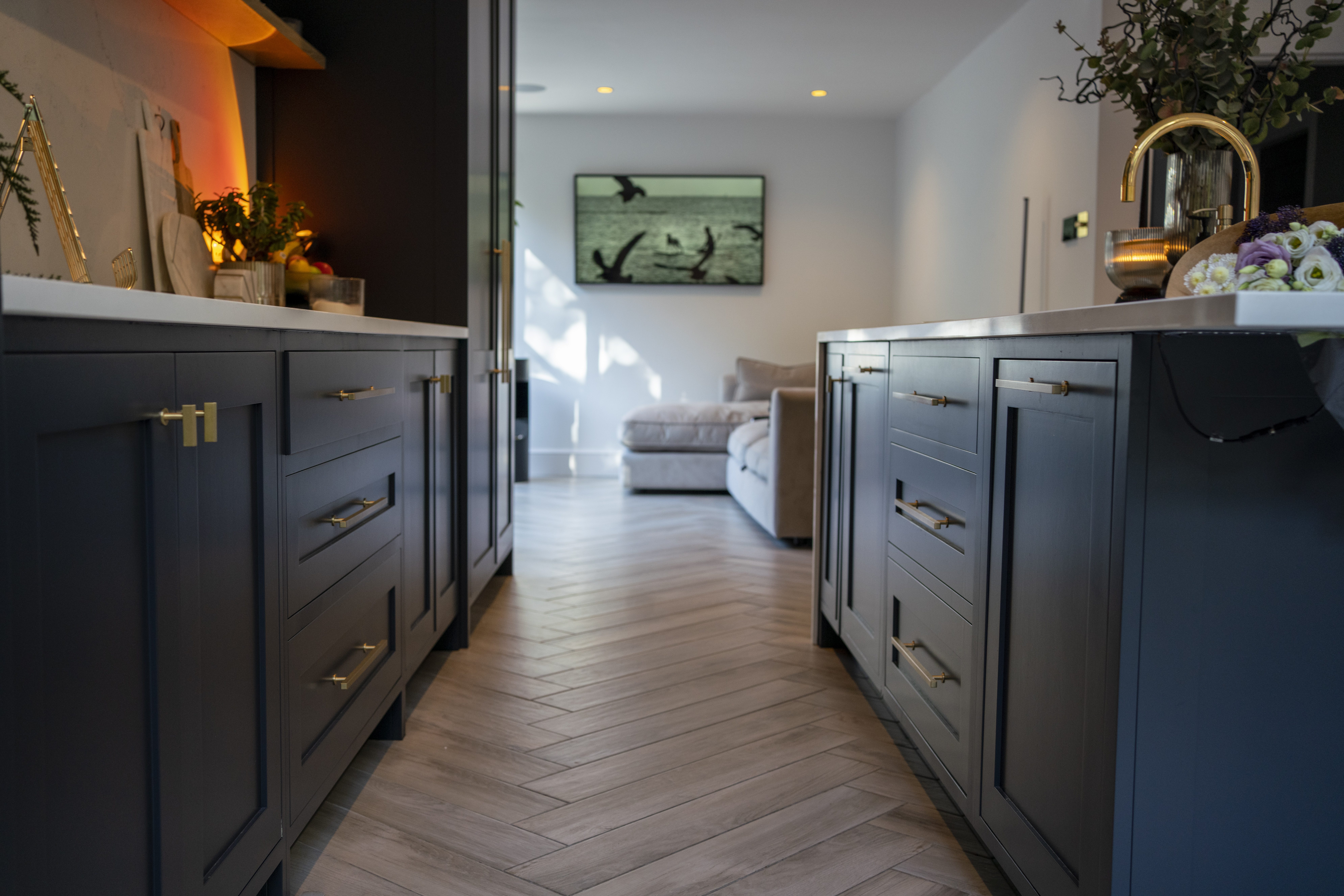 Long kitchen view with an Olympus White Quartz island worktop running through the centre of dark cabinetry