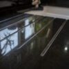 Close up of Absolute Black Granite worktop showing precision cut drainer grooves with reflections on the polished surface near the sink.