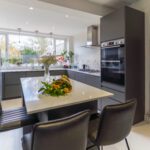 Blanco Zeus Quartz island worktop with bright white surface and seating in a modern kitchen with dark cabinetry