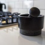 Blanco Zeus Quartz worktop close-up with a black stone mortar and pestle on a bright white surface near the hob
