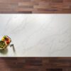 White Calacatta Quartz slab displayed on a wooden surface with food styling and grey veining