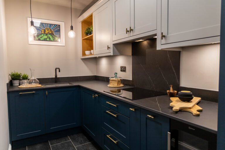 Aragon Porcelain worktops across a fitted kitchen, showing dark veined Porcelain surfaces with navy cabinetry and warm lighting